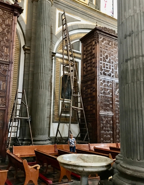       Interior of a church with ladders and decorative panels.
  