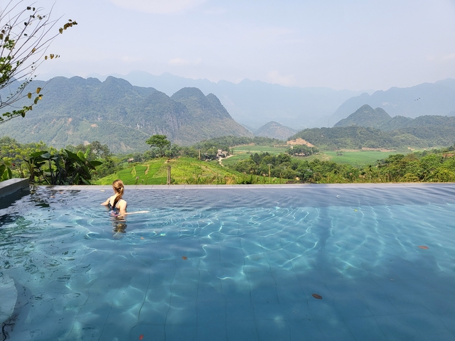 Person swimming in infinity pool with mountain view in the background.