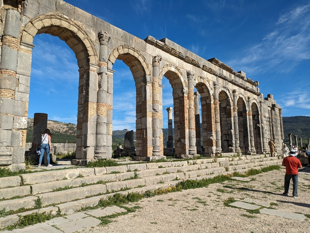Ancient stone arch ruins with tourists.