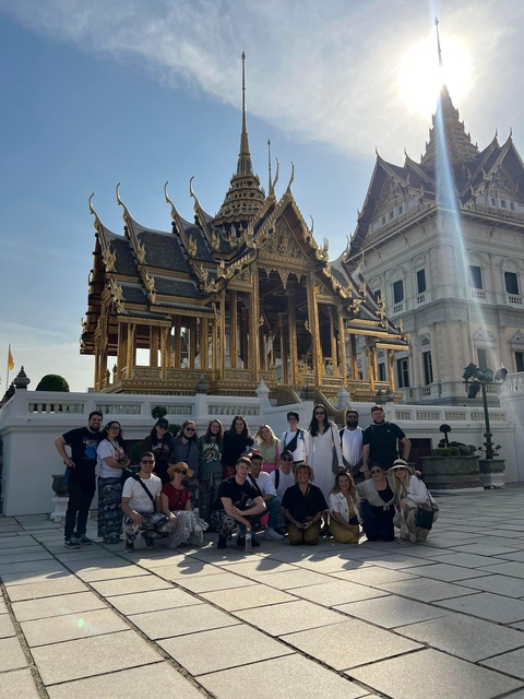 Large group posing in front of a golden temple.