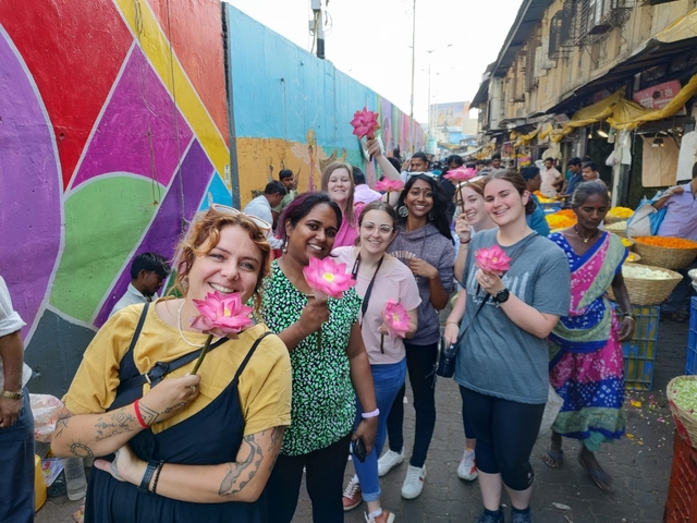 Group of people in a colorful market, holding flowers.