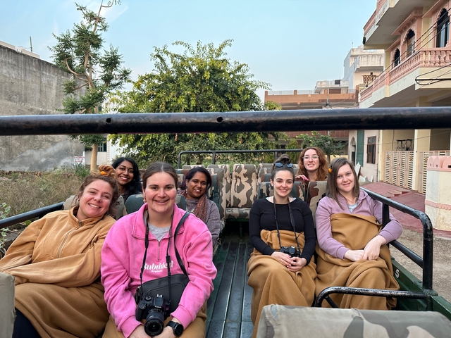 Group of women in a jeep, wrapped in blankets.