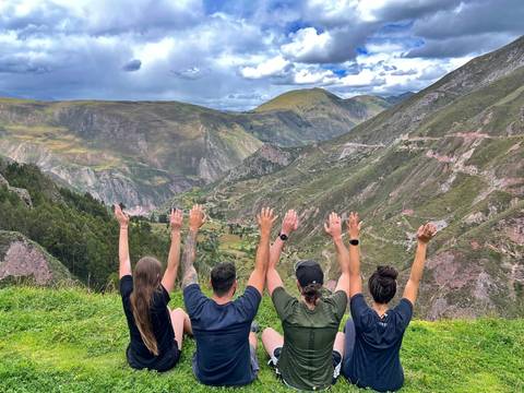 Four people with arms raised overlooking a valley.