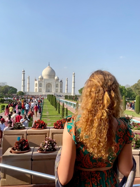 The Taj Mahal with a woman looking at it.