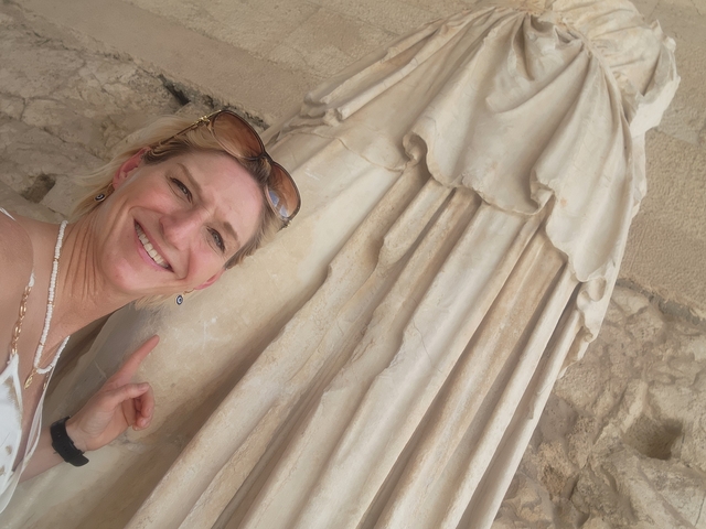       Person posing with an ancient statue.
  