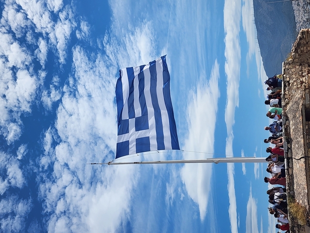       Large blue and white flag with people gathered beneath.
  