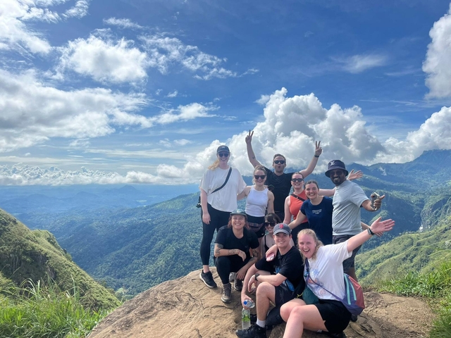 Group of people posing on a mountain with a scenic view.