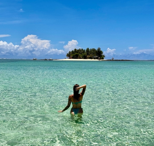       Woman in the water looking at an island in the distance.
  