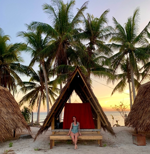 Small structure with palm trees by the beach during sunset.