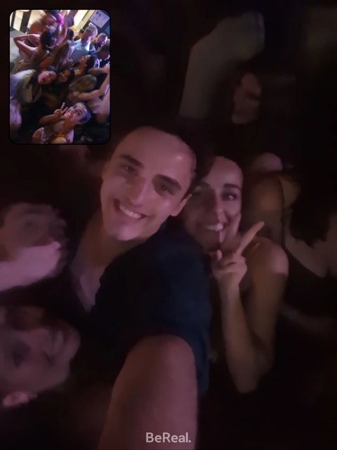 Close-up selfie of two people in a dimly lit environment.