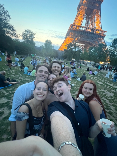 Selfie of a group in a park setting with the Eiffel Tower background.