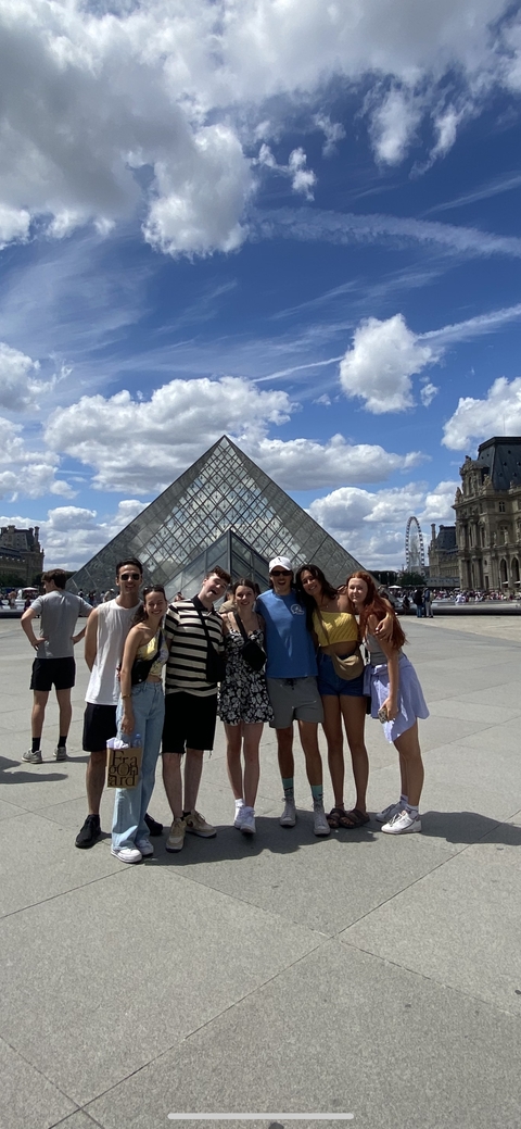 Group of people posing in front of the Louvre Pyramid.