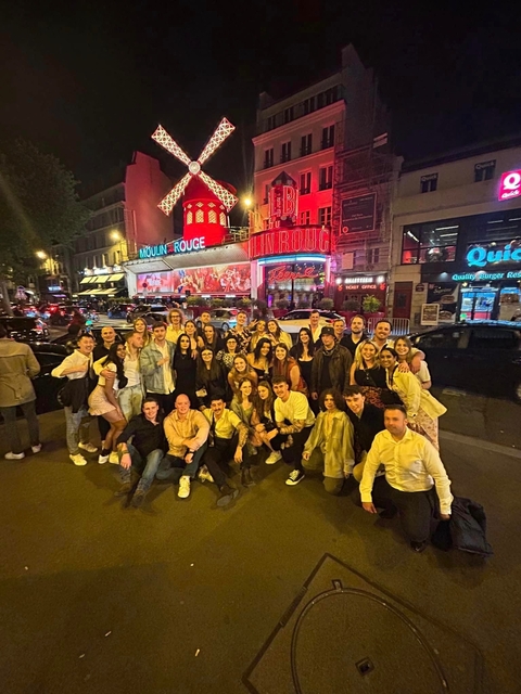 A large group of people outside the Moulin Rouge at night.