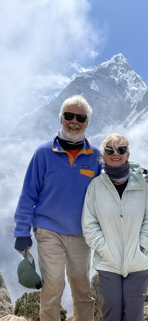 A couple posing with snowy mountains in the backdrop.