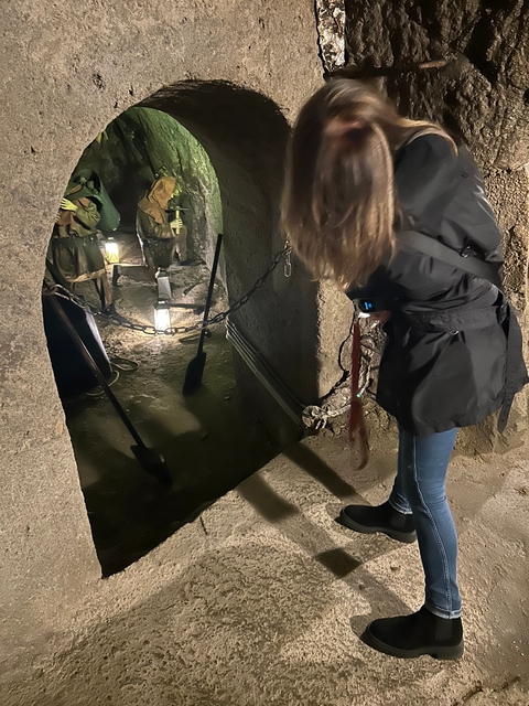 Person exploring an underground tunnel with lighting.