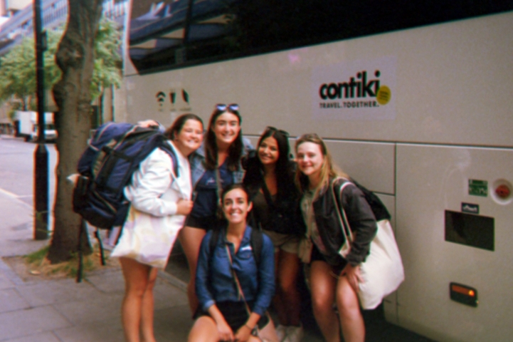 Group of people posed in front of a tour bus.
