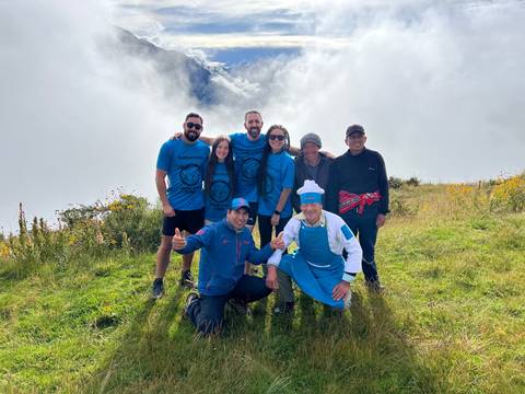 Group of people in matching shirts posing in a cloudy mountain setting.
