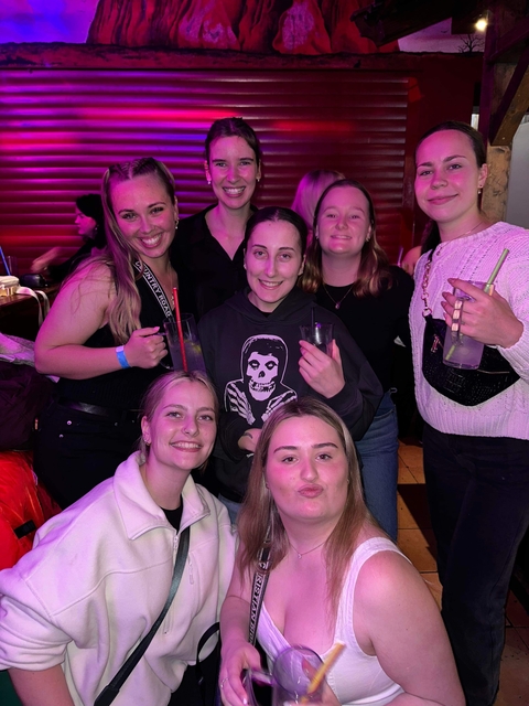 Young people posing indoors with purple lighting.