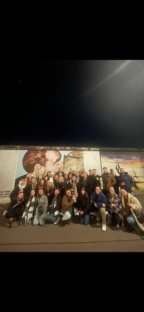 Group in front of a part of the Berlin Wall with famous mural.