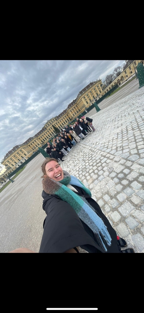 Person taking a selfie with a large group in front of Schloss Schönbrunn.