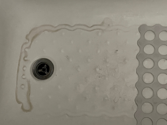 Close-up of a shower drain and mat.