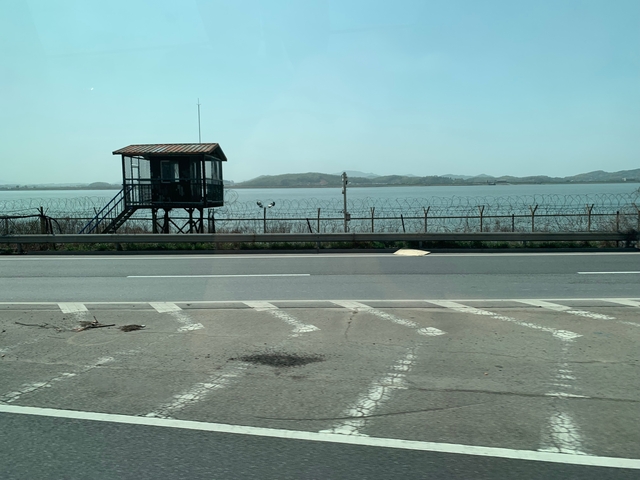 Guard tower and barbed fence viewed from a distance.