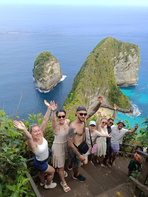 People posing with high cliffs and turquoise waters in the background.