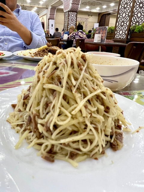Plate of traditional noodles with sliced meat in a pyramid shape.