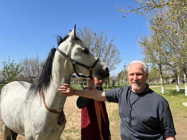       Person posing with a horse in an outdoor setting.
  