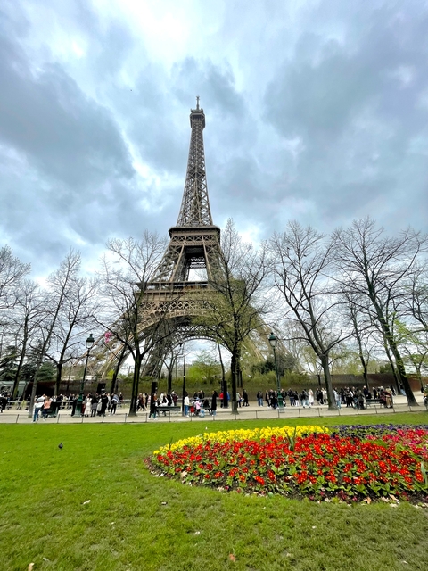 Eiffel Tower with partially leafless trees and people walking.