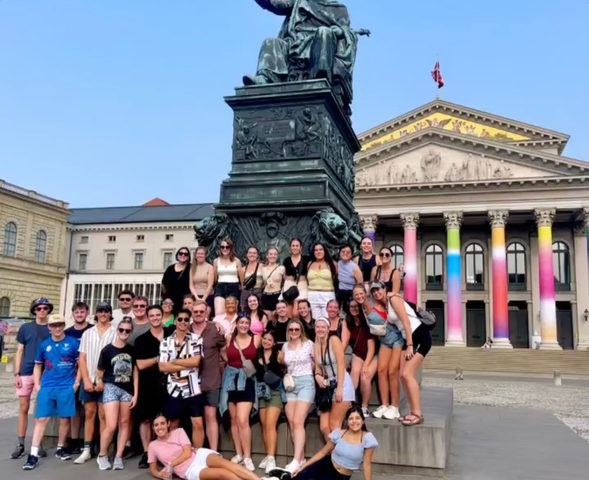 A large group of people posing in front of a monument.
