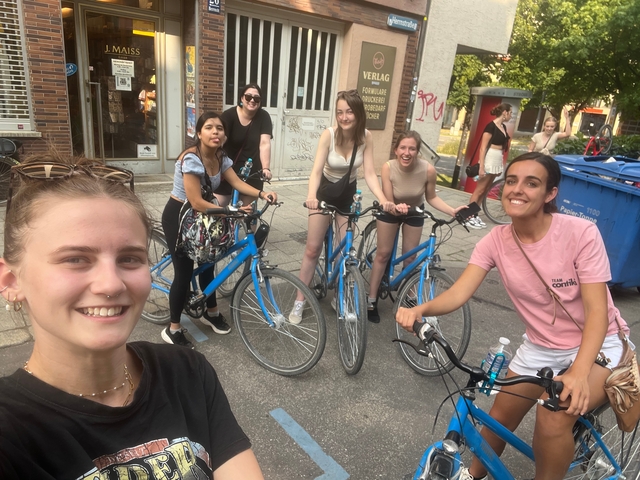 A group of people on bicycles smiling for a photo in a city setting.