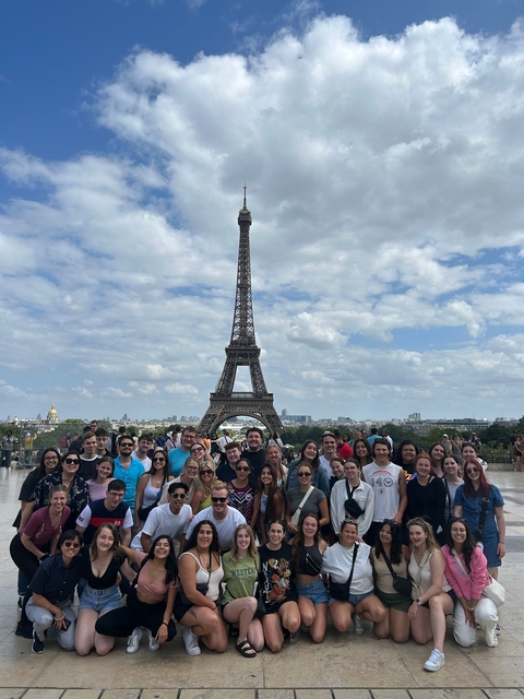 A group of people posing in front of the Eiffel Tower.