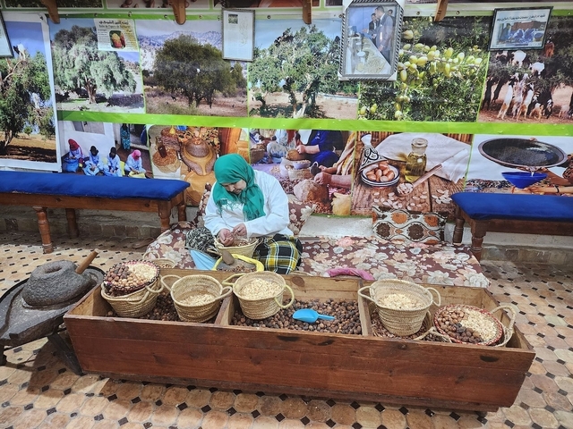 A person working with baskets and argan nuts, possibly in a cooperative.