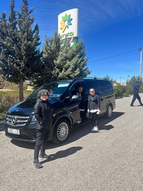 Three people posing next to a black Mercedes van.