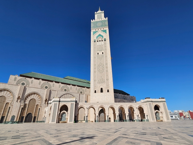       The majestic Hassan II Mosque with its tall minaret under a clear blue sky.
  