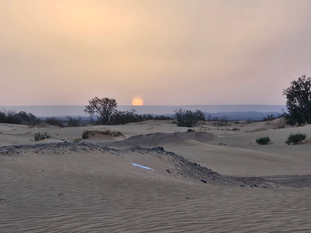       Sun setting over a tranquil desert landscape.
  