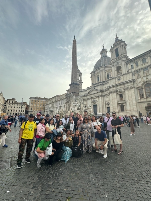 A group of tourists posing in front of a historic building in a city square.