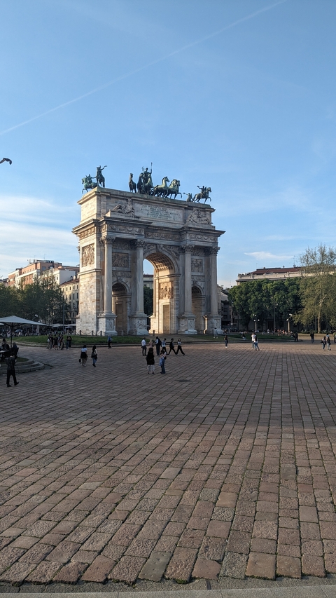 A historic arch with people walking through a plaza.