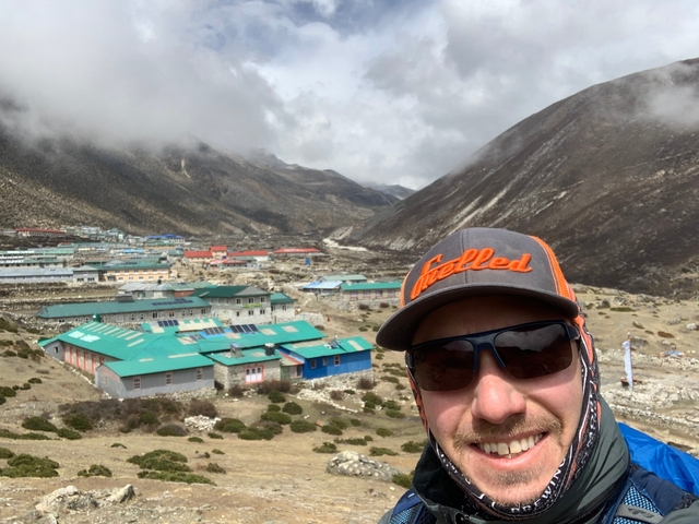      A man with a view of a small village and mountains in the background.
  