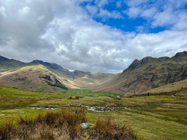       A dramatic view of mountains and valleys with clouds in the sky.
  