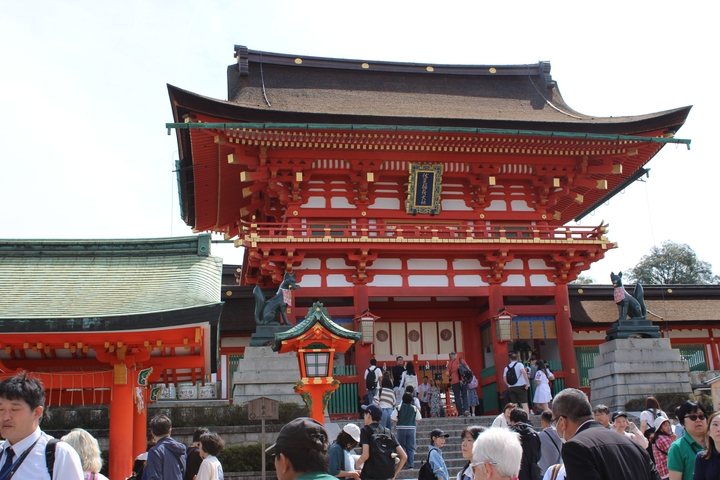       A red traditional Japanese building with visitors.
  