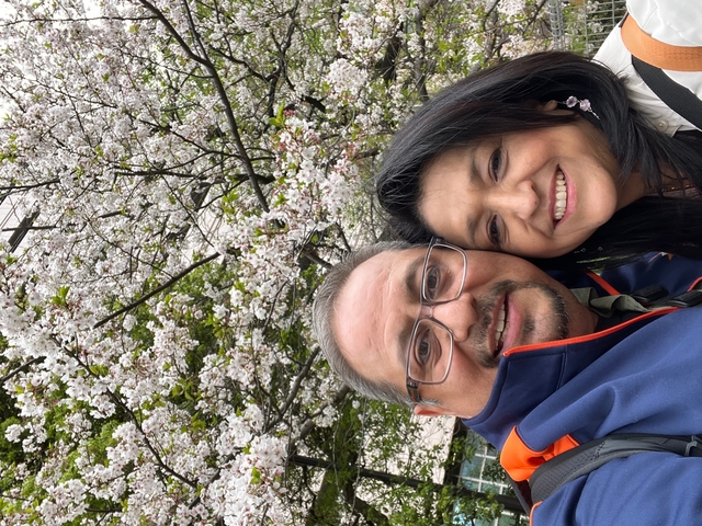       Two people in front of cherry blossom trees.
  