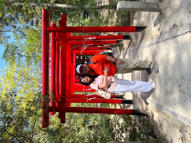       Two tourists posing among red torii gates.
  