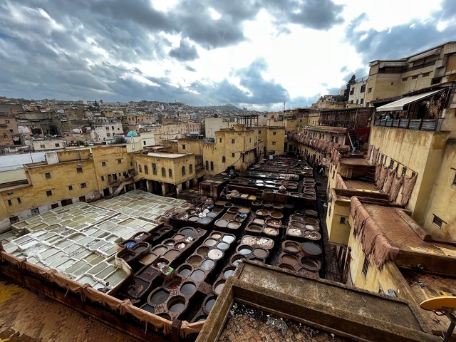 Traditional tannery with colorful dye pits and yellow buildings.