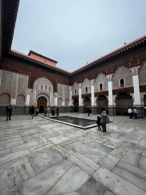 Courtyard with people around a reflective pool in a traditional Moroccan building.