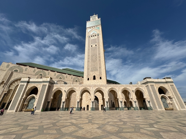       A large mosque with a tall minaret against a blue sky.
  