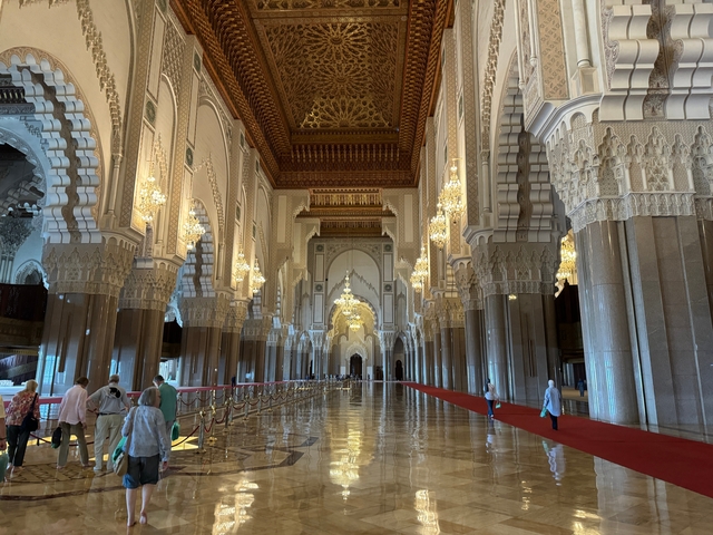       Interior of a grand mosque with chandeliers and intricate architecture.
  