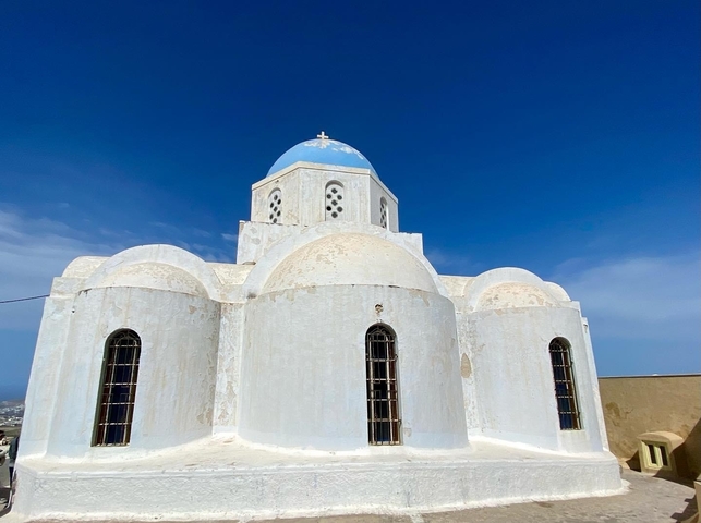 Whitewashed domed church with a blue dome under a clear sky.