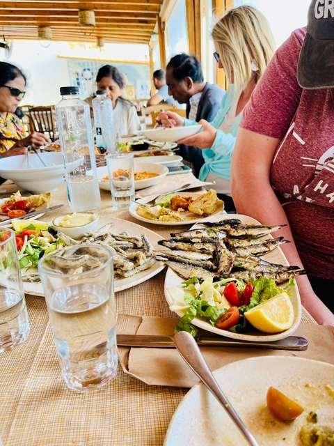 Traditional Greek meal with various dishes and people at a table.